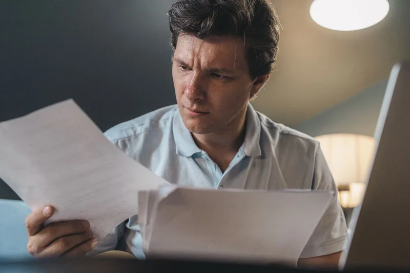 A person reading through documents at a desk in warm light