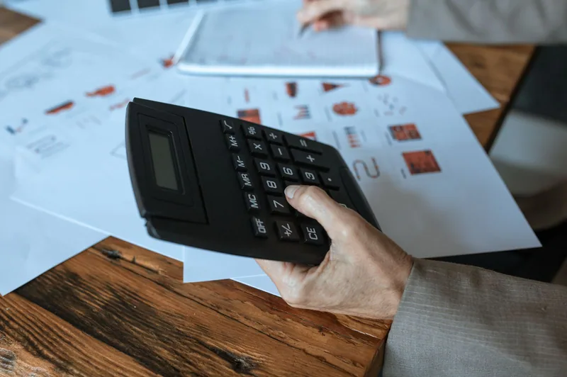 A calculator on a desk alongside printed charts
